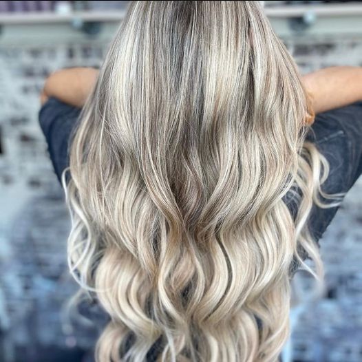 blond girl showing off her new hair extensions done by salons near me